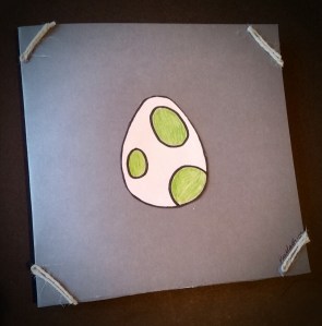 Front of handmade birthday card of Yoshi's egg on cardstock with twine accents