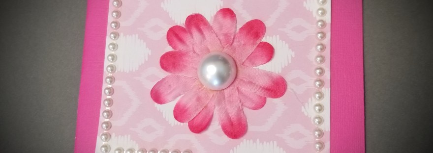 Handmade mothers day card of a pink silk flower on pink patterned cardstock with pearl accents